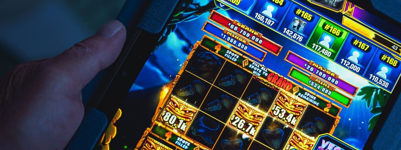 A person operating a slots game on a handheld tablet.
