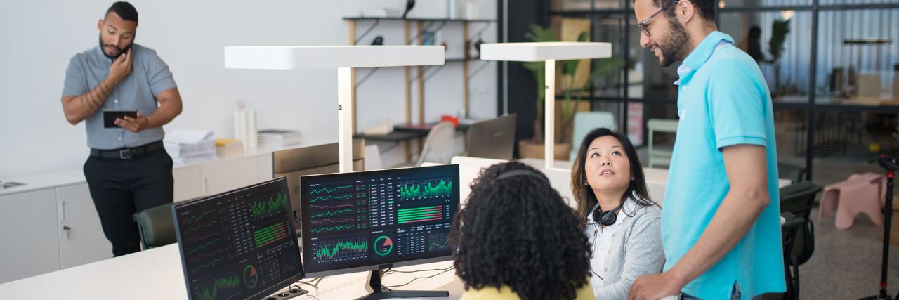 Colleagues reviewing monitoring dashboards together in an office.