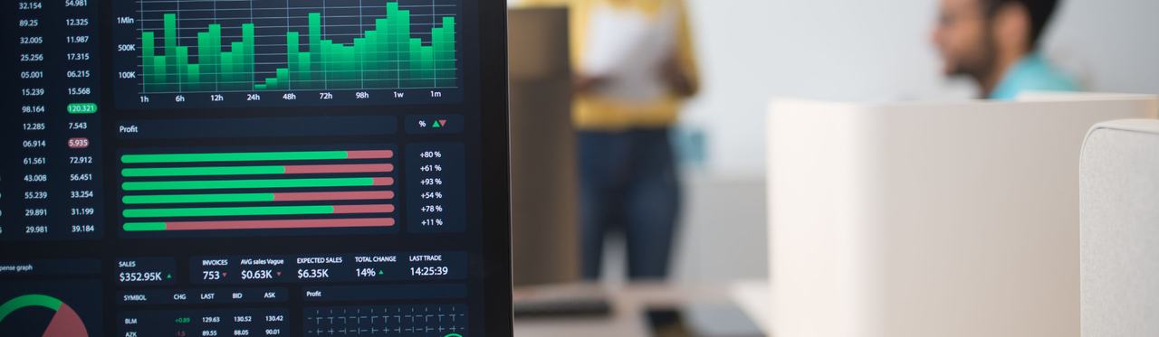 A desktop monitor displaying live trading-style dashboards in an office.